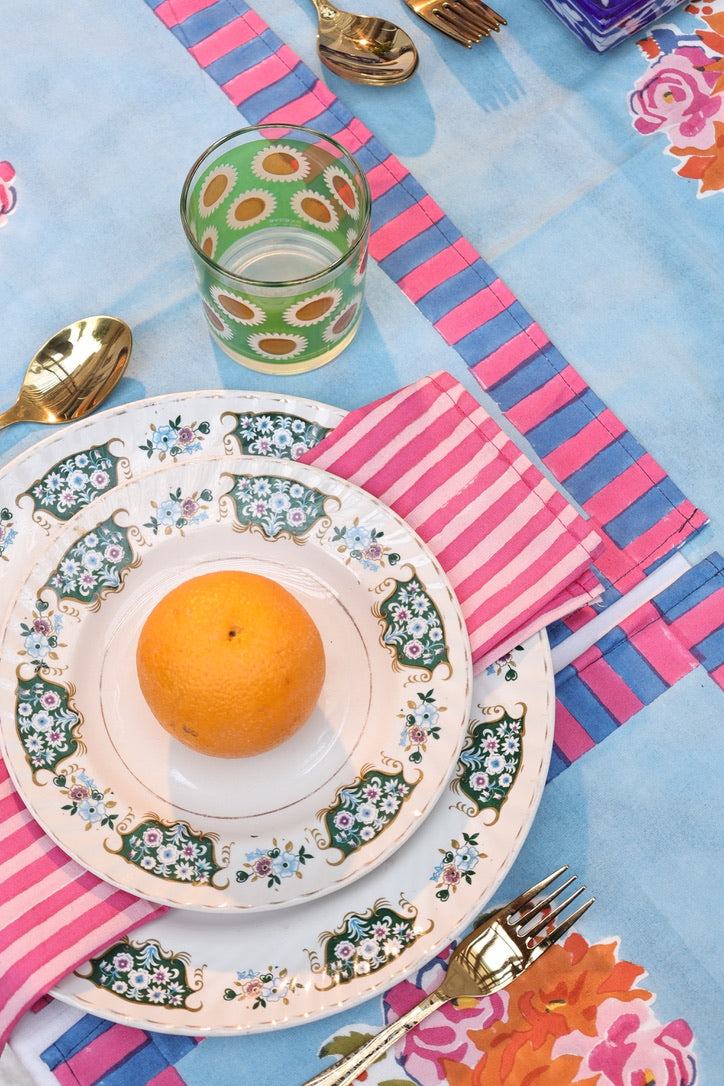 Decorative napkins with alternating bands of pink and blue, designed to create a structured, curated look on a modern dining table.